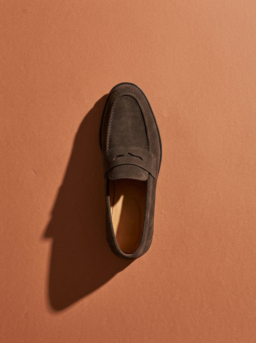 Mocasín Estribo de ante color chocolate visto desde arriba sobre fondo terracota