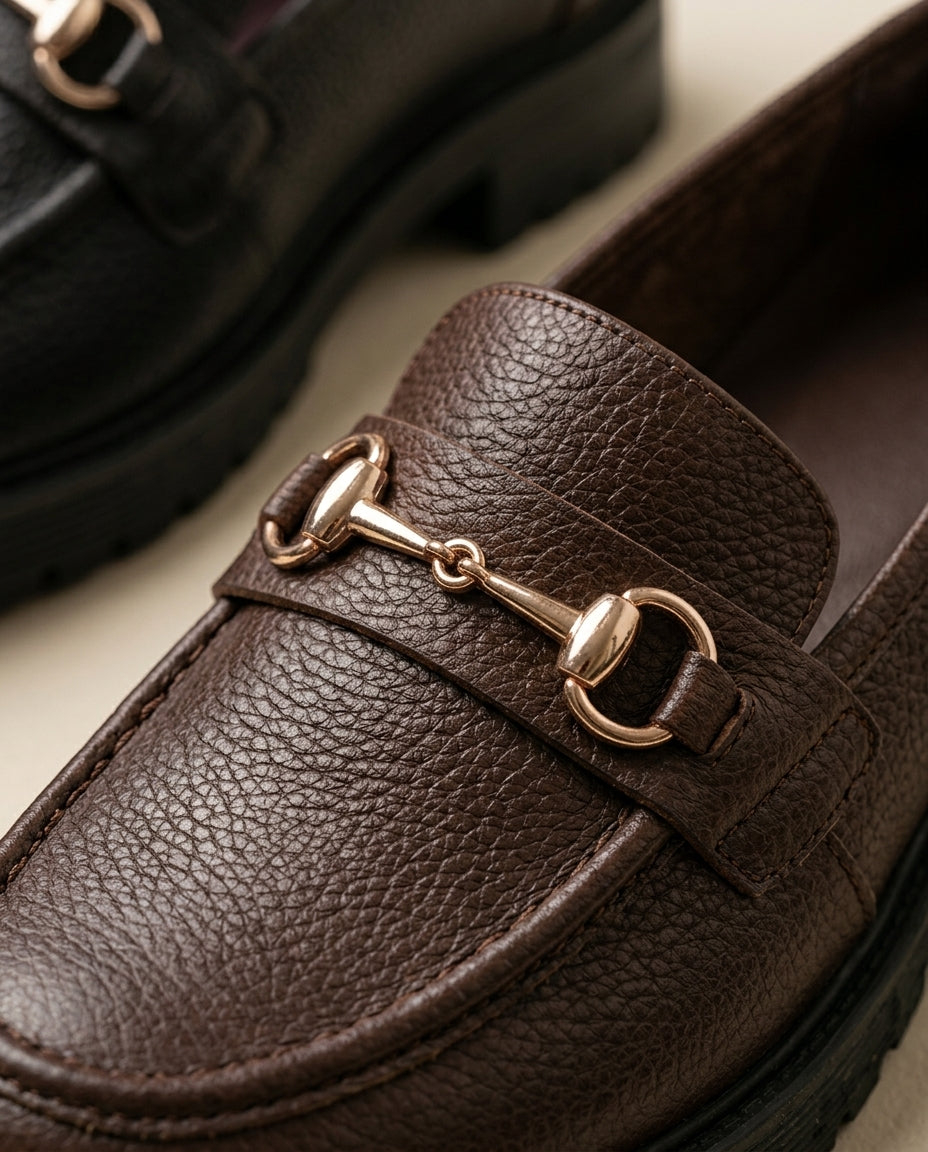 Mocasín Traviesa chocolate, detalle de la piel granulada y el bocado dorado