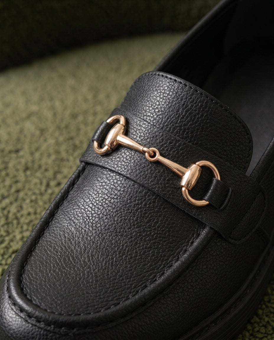 Mocasín Traviesa negro, detalle de la piel granulada y el bocado dorado