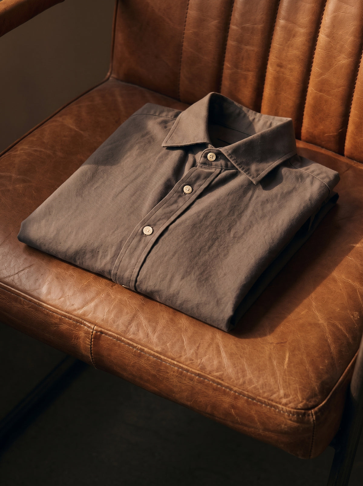 Camisa de hombre doblada sobre un sillón de piel